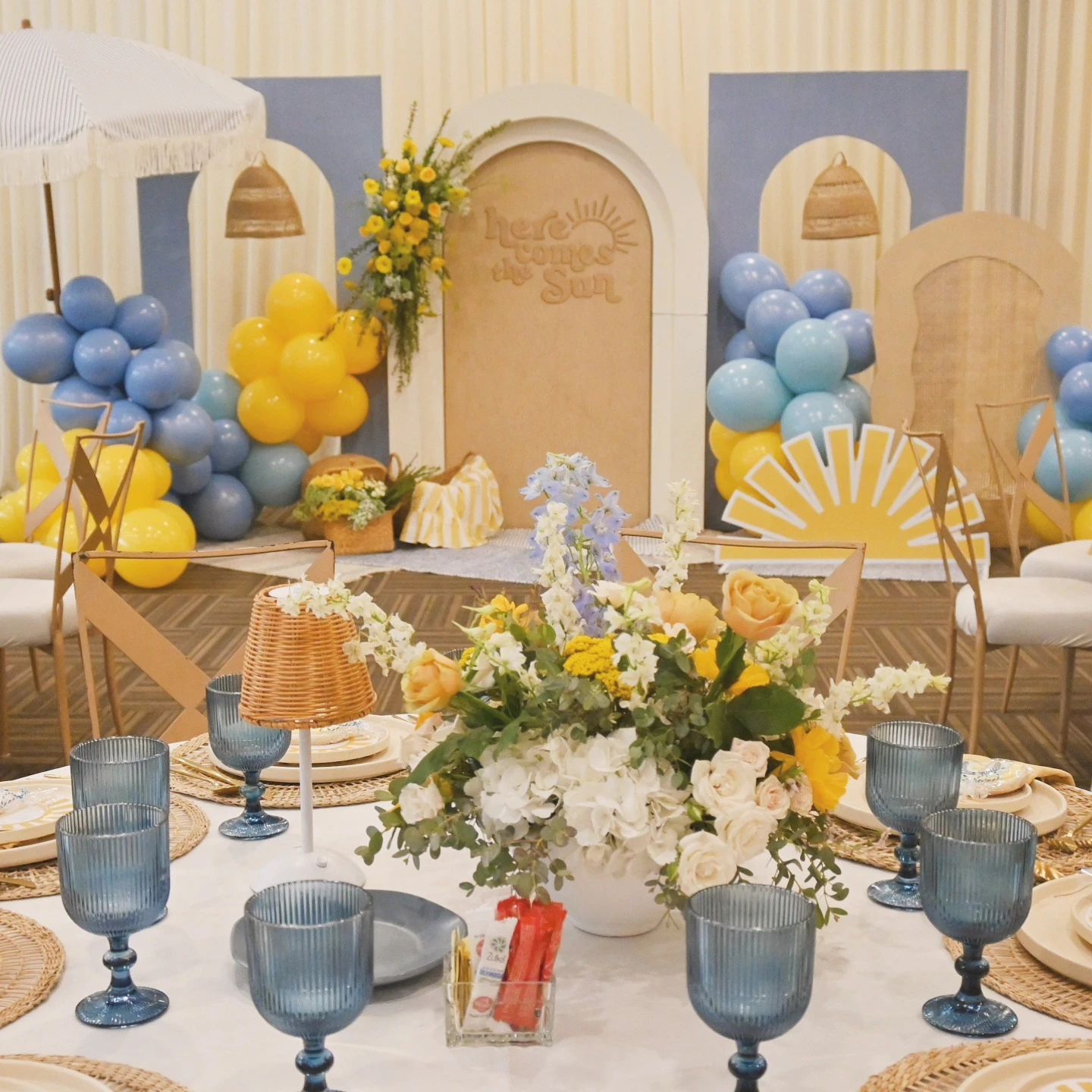 Wide view of a 'Here Comes the Sun' baby shower with coordinated table settings and a large backdrop.