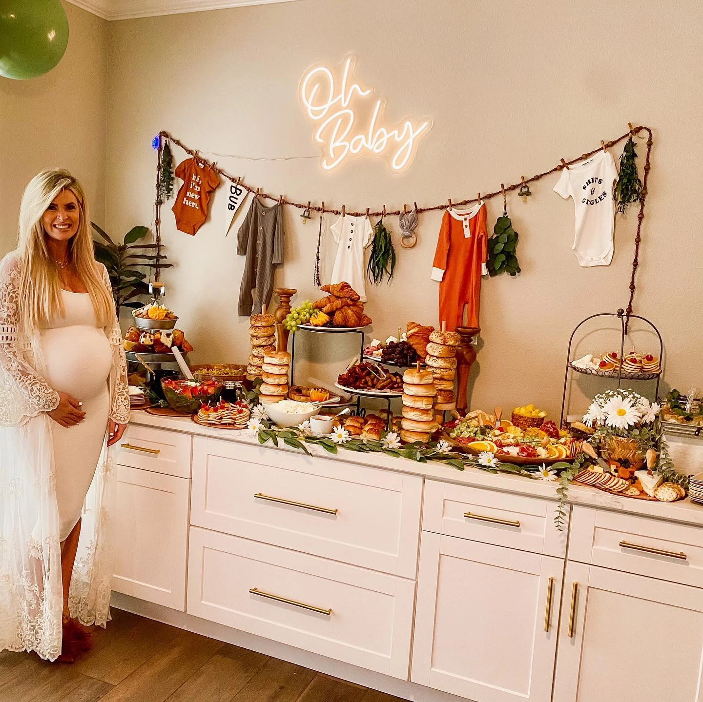 An abundant baby shower brunch grazing table featuring stacked bagels, tiered pastry stands, fruit platters, and charcuterie boards.