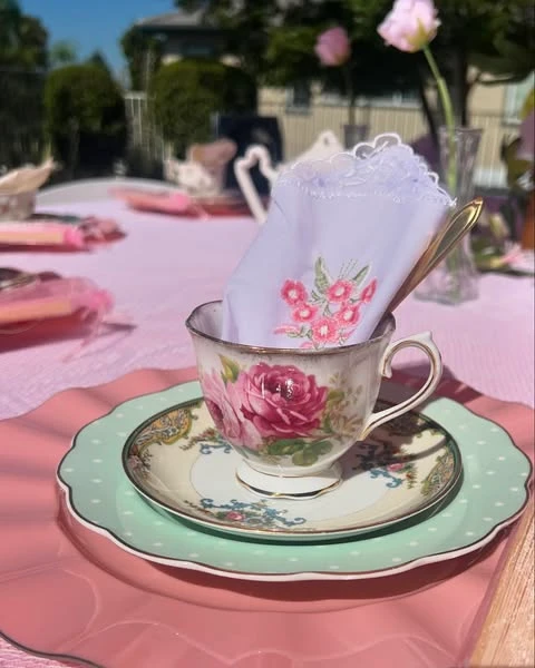 A vintage floral teacup place setting with layered pink and mint green plates for a tea party bridal shower.