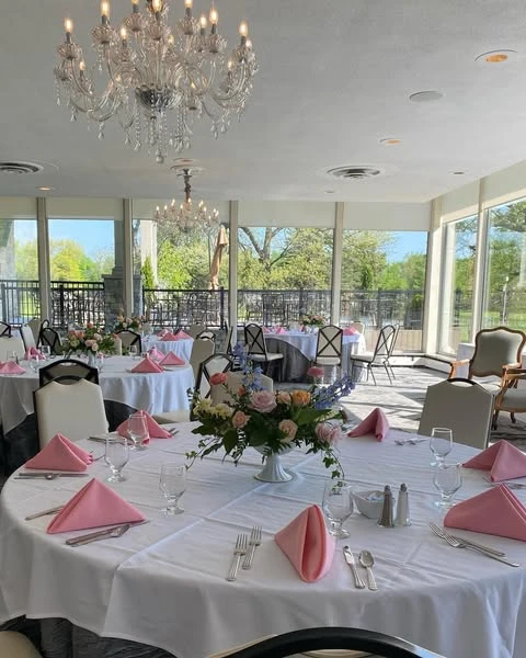 Elegant event room with round tables set for a spring bridal shower with pink napkins and floral centerpieces.