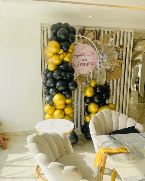 Black and gold balloon arch framing a 'Congratulations On Your Retirement' sign.