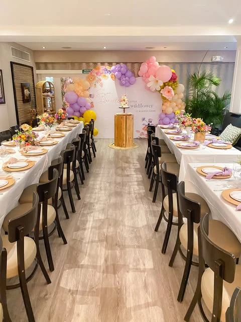 Room view of a wildflower baby shower with long tables and a balloon arch backdrop.