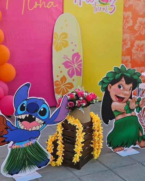 Stitch and Lilo character cutouts standing next to a decorative yellow surfboard prop and leis.