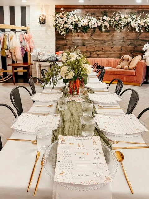 Long dining table set for a Peter Rabbit baby shower with game cards at each place.