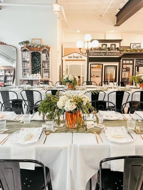 A wide view of long dining tables set for a rustic Peter Rabbit baby shower.
