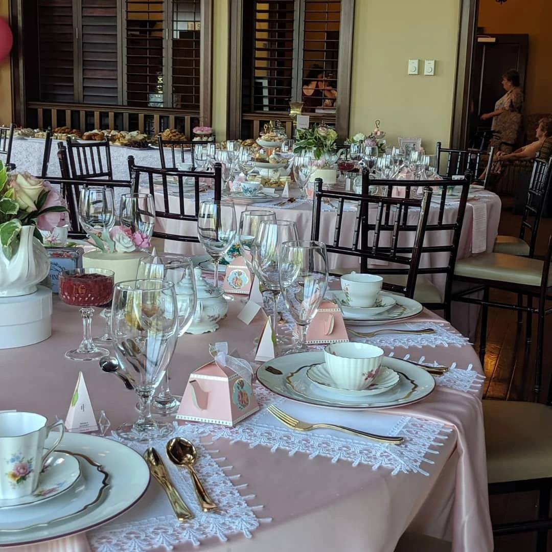 Multiple round tables set for a vintage tea party bridal shower with pink tablecloths and mismatched china.