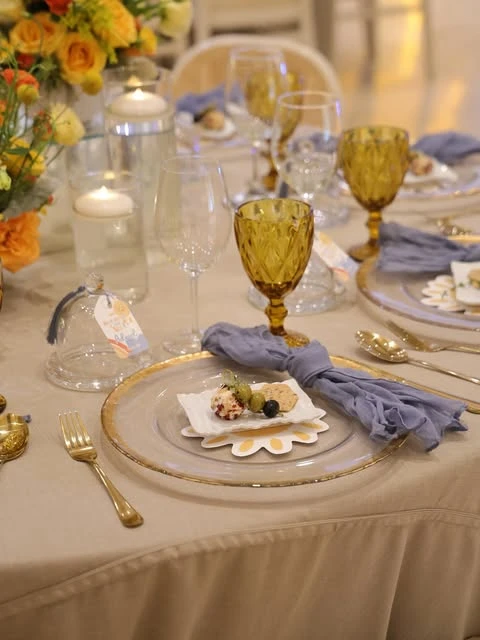 An elegant baby shower place setting featuring a sun-shaped plate, gold cutlery, and a dusty blue napkin.