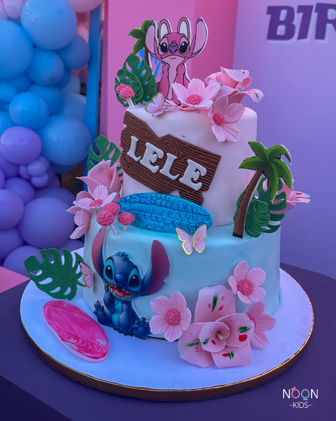 Two-tier Stitch and Angel birthday cake with tropical fondant decorations.