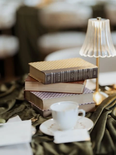 A stack of vintage books and a small table lamp used as a centerpiece for a literary-themed bridal shower.