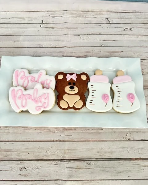 Assortment of custom sugar cookies for a teddy bear baby shower, including a bear and baby bottles.