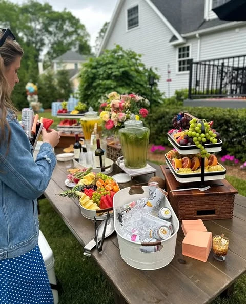 Outdoor food and drink table decorated with a small wildflower bouquet for a baby shower.