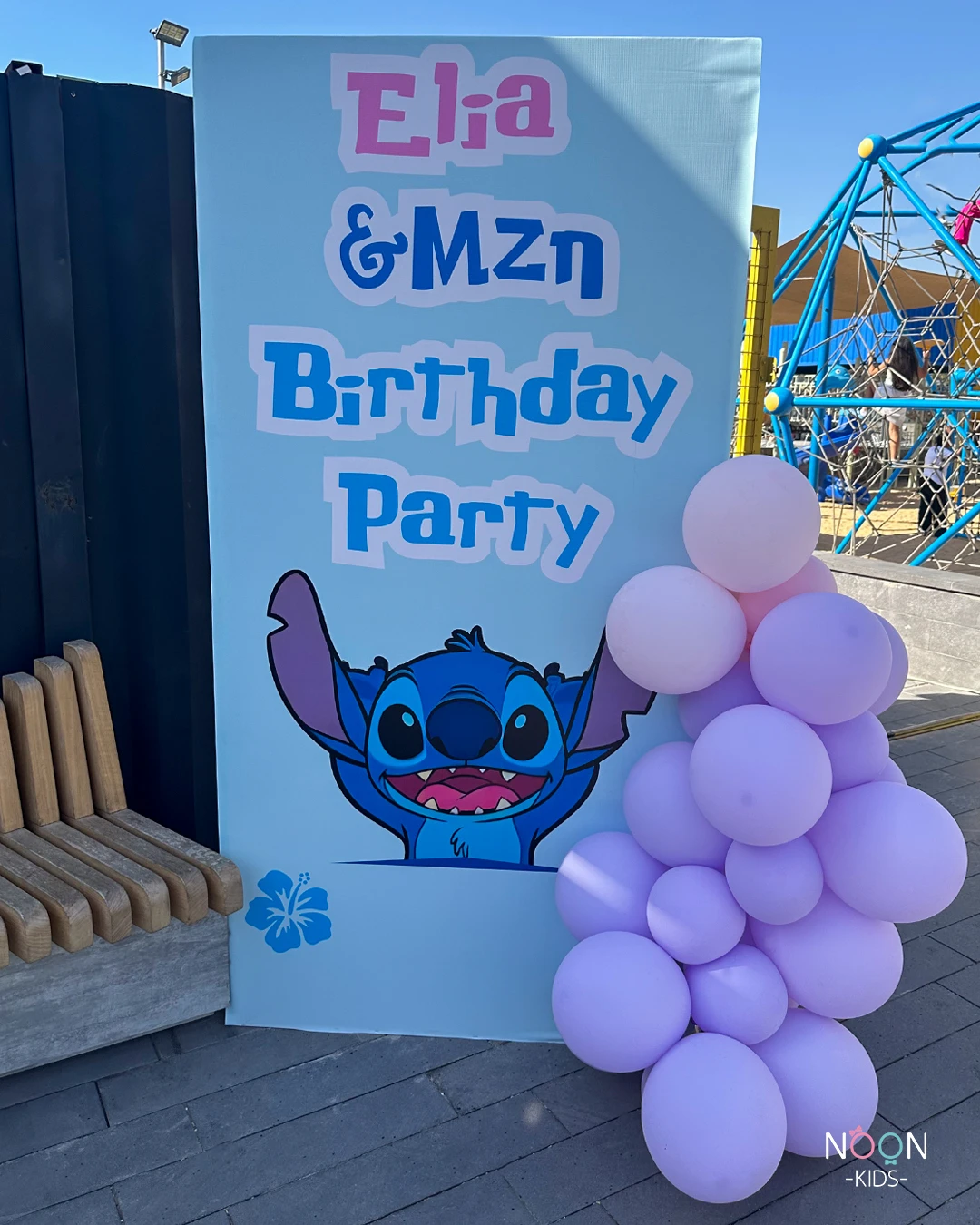 Personalized Stitch birthday party welcome sign with a purple and pink balloon garland.