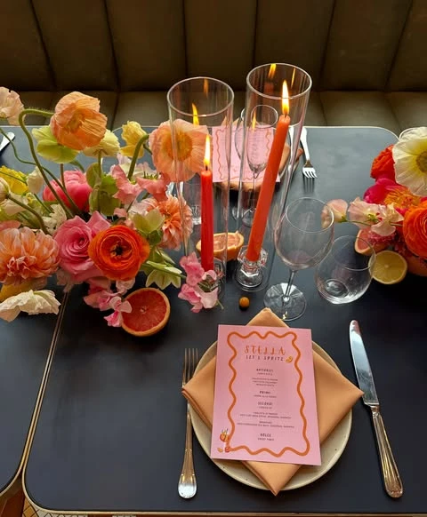 A colorful spring bridal shower tablescape with pink and orange flowers, taper candles, and sliced blood oranges.