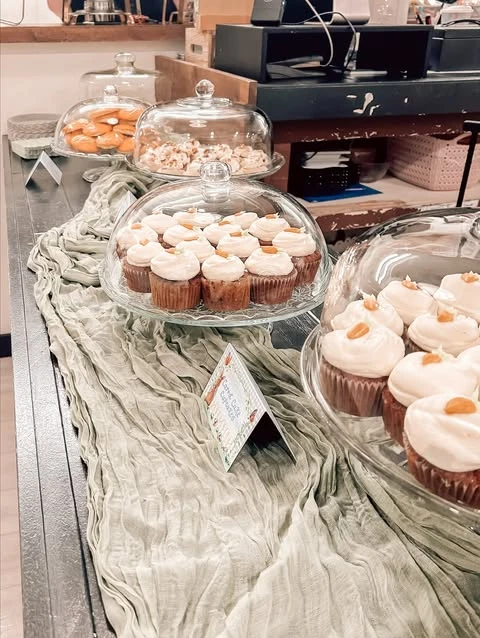 Carrot cake cupcakes with cream cheese frosting on a glass stand for a Peter Rabbit baby shower.