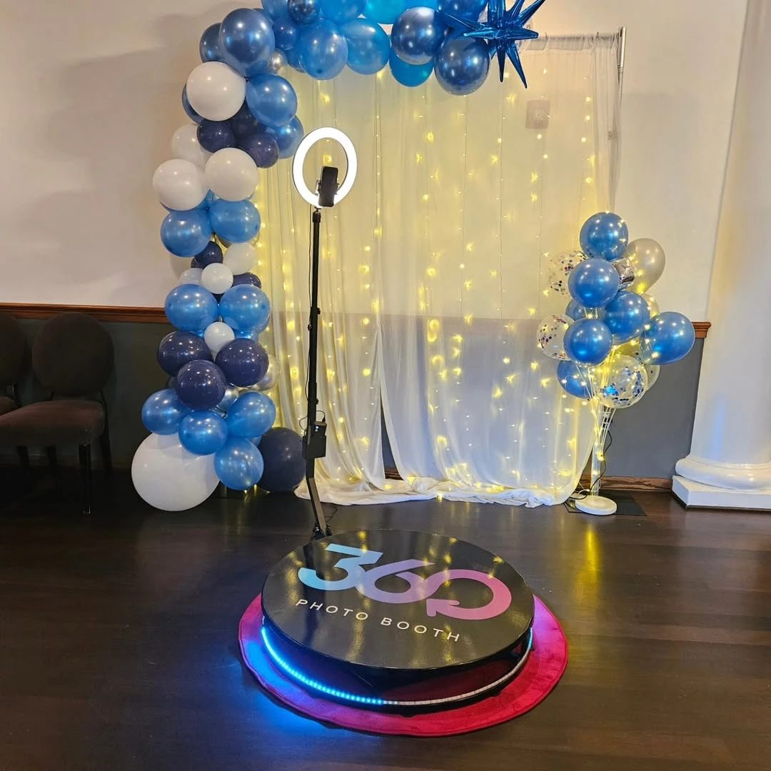 A 360 photo booth with a ring light and lighted curtain backdrop set up for a party.