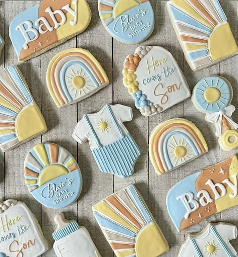 A collection of 'here comes the sun' and 'here comes the son' themed baby shower cookies.