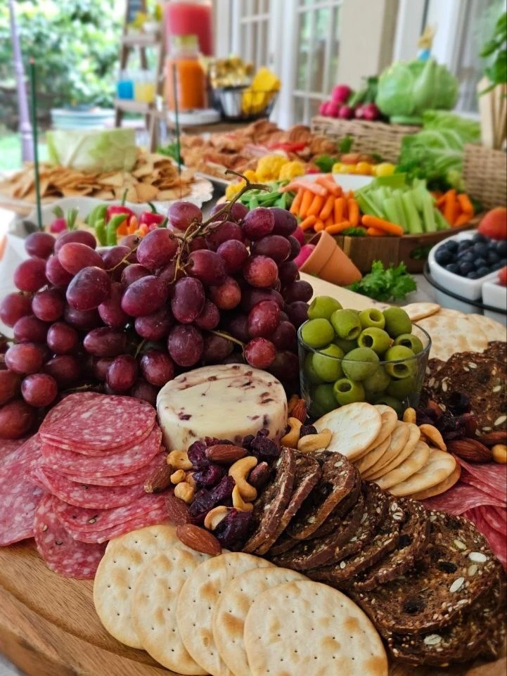 A rustic charcuterie board with grapes, salami, cheese, and olives for a Peter Rabbit baby shower.