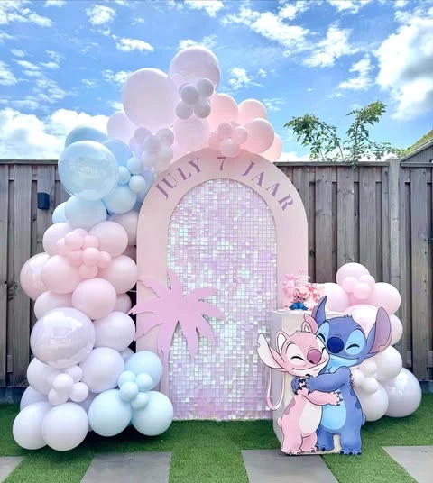 A Stitch and Angel themed birthday party backdrop with a pastel balloon arch and a shimmer wall.