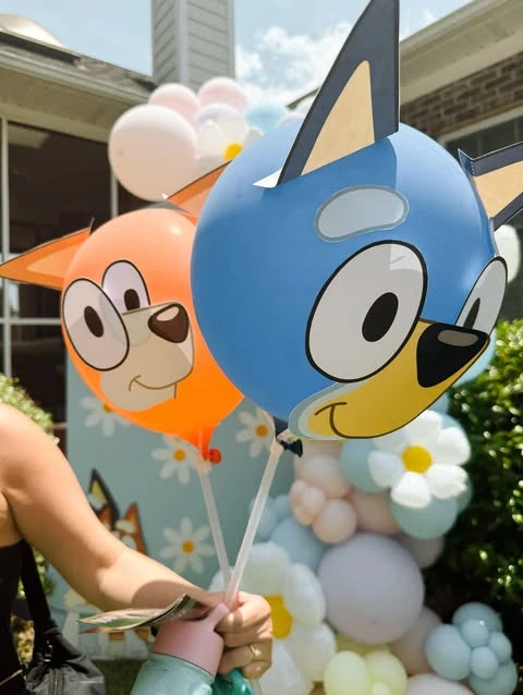 DIY Bluey and Bingo balloons made from paper cutouts on orange and blue balloons.