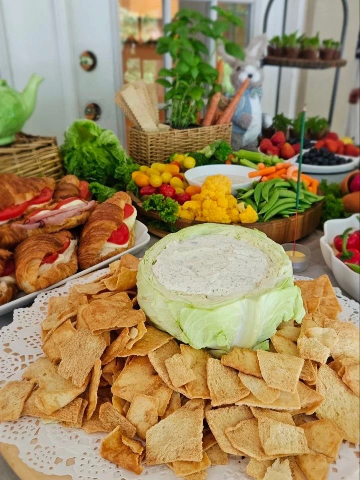 A creative Peter Rabbit party food idea using a hollowed-out cabbage as a serving bowl for dip, surrounded by crackers.