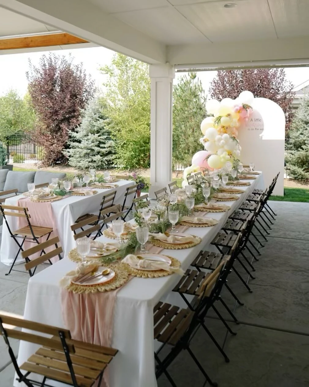 Long baby shower dining table with rustic wooden chairs and a dusty rose table runner.