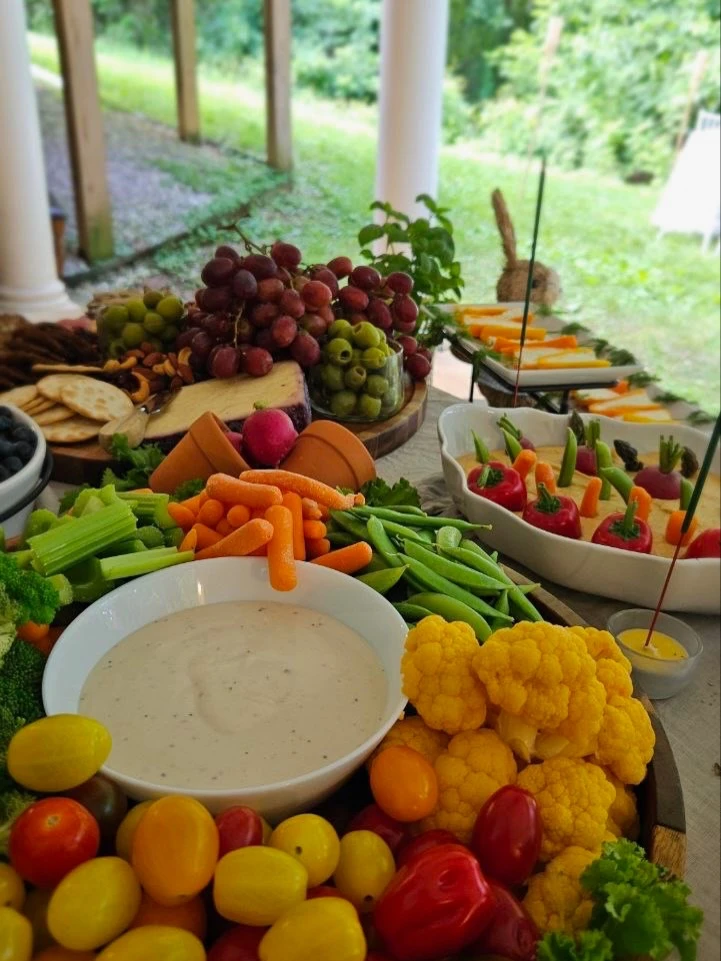 A colorful garden vegetable platter for a Peter Rabbit baby shower, with tomatoes, cauliflower, carrots, and dip.