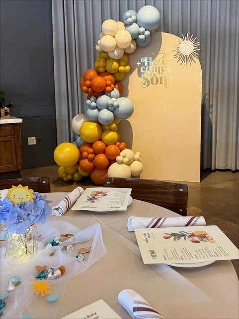 Baby shower table setting with a sun-themed centerpiece and menus.