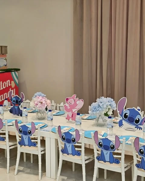A Stitch-themed birthday party table with character cutouts on the back of each chair and larger standees on the table.