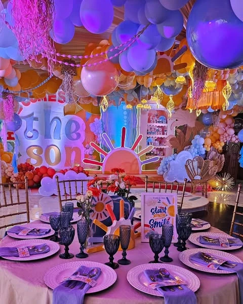A 'Here Comes the Son' baby shower with a large sun backdrop and an elaborate balloon installation on the ceiling.