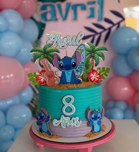 A teal and lavender birthday cake decorated with Stitch, surfboard, and palm tree toppers for a Stitch birthday party.