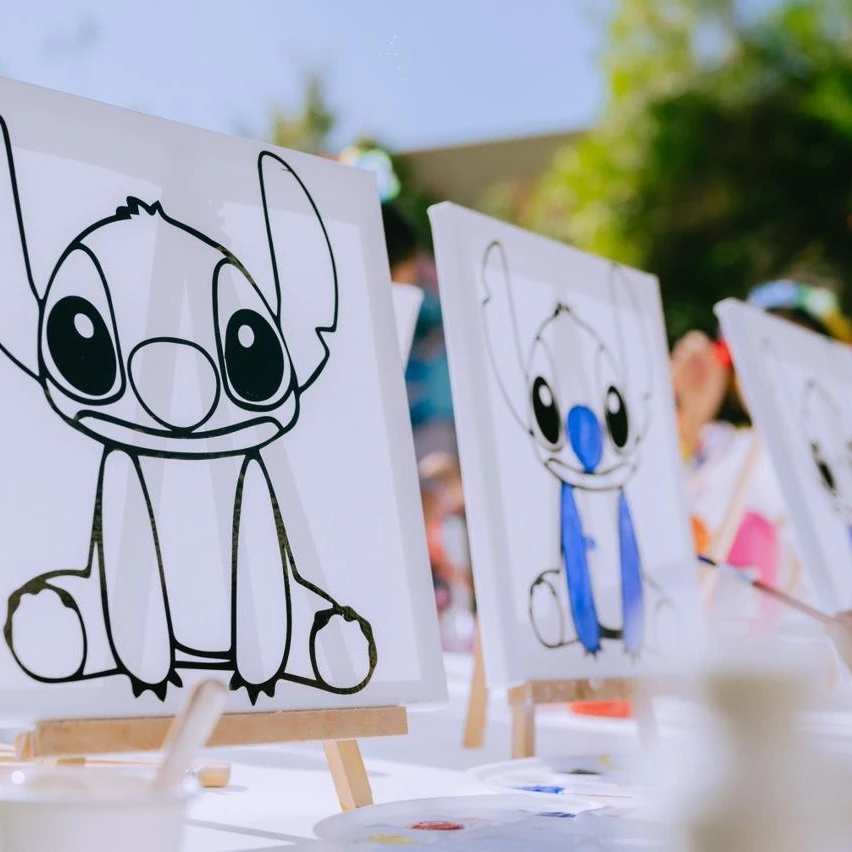 of pre-outlined Stitch canvases on mini easels for a kids' painting party.