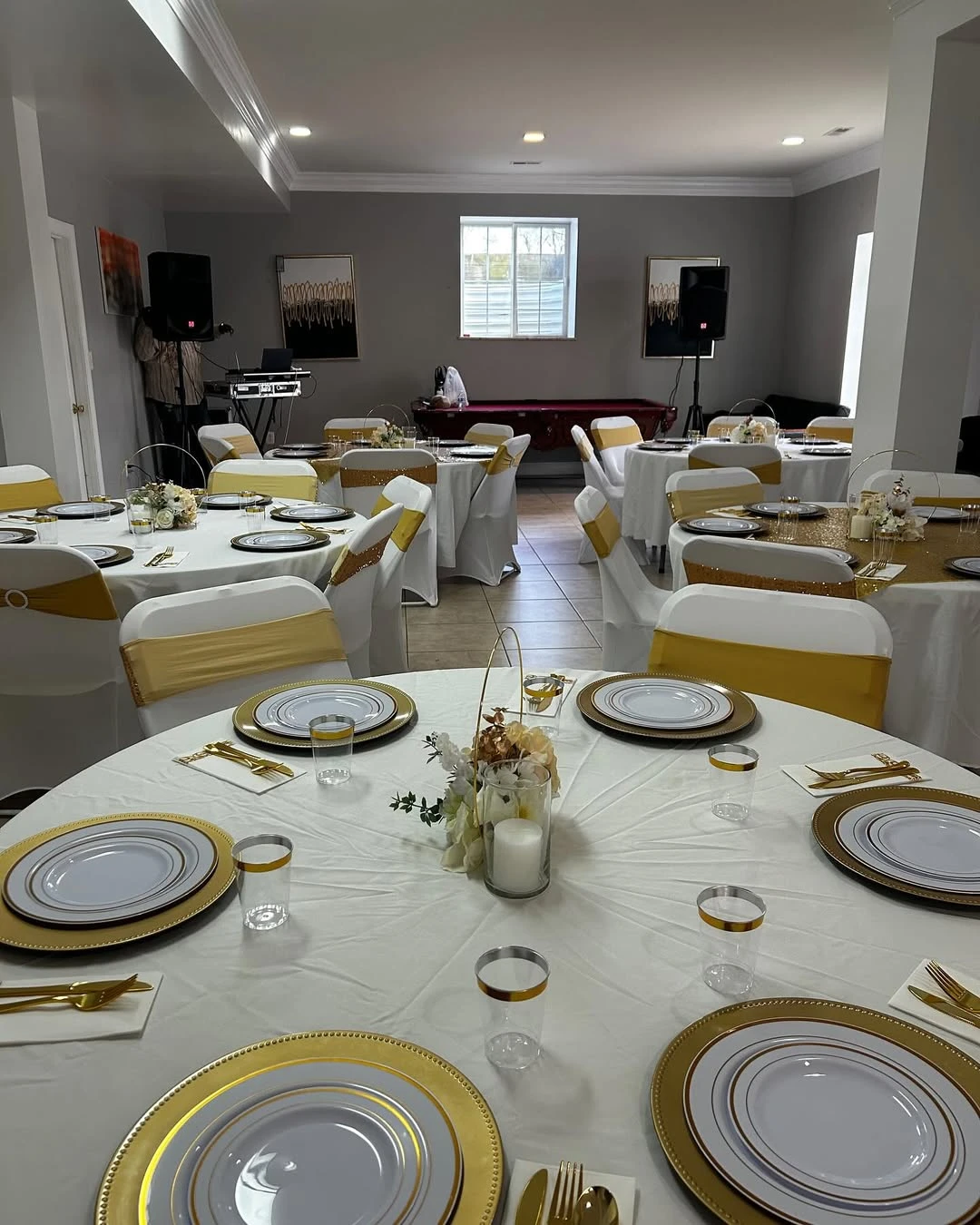 Tables set for a retirement party with white tablecloths and coordinated gold place settings.