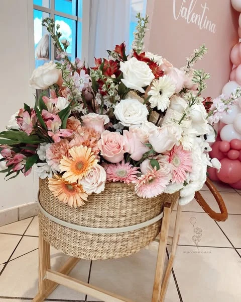 Large floral arrangement in a woven basket with pink and white flowers.