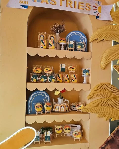Themed 'Here Comes the Sun' sugar cookies displayed on a yellow arched shelf.