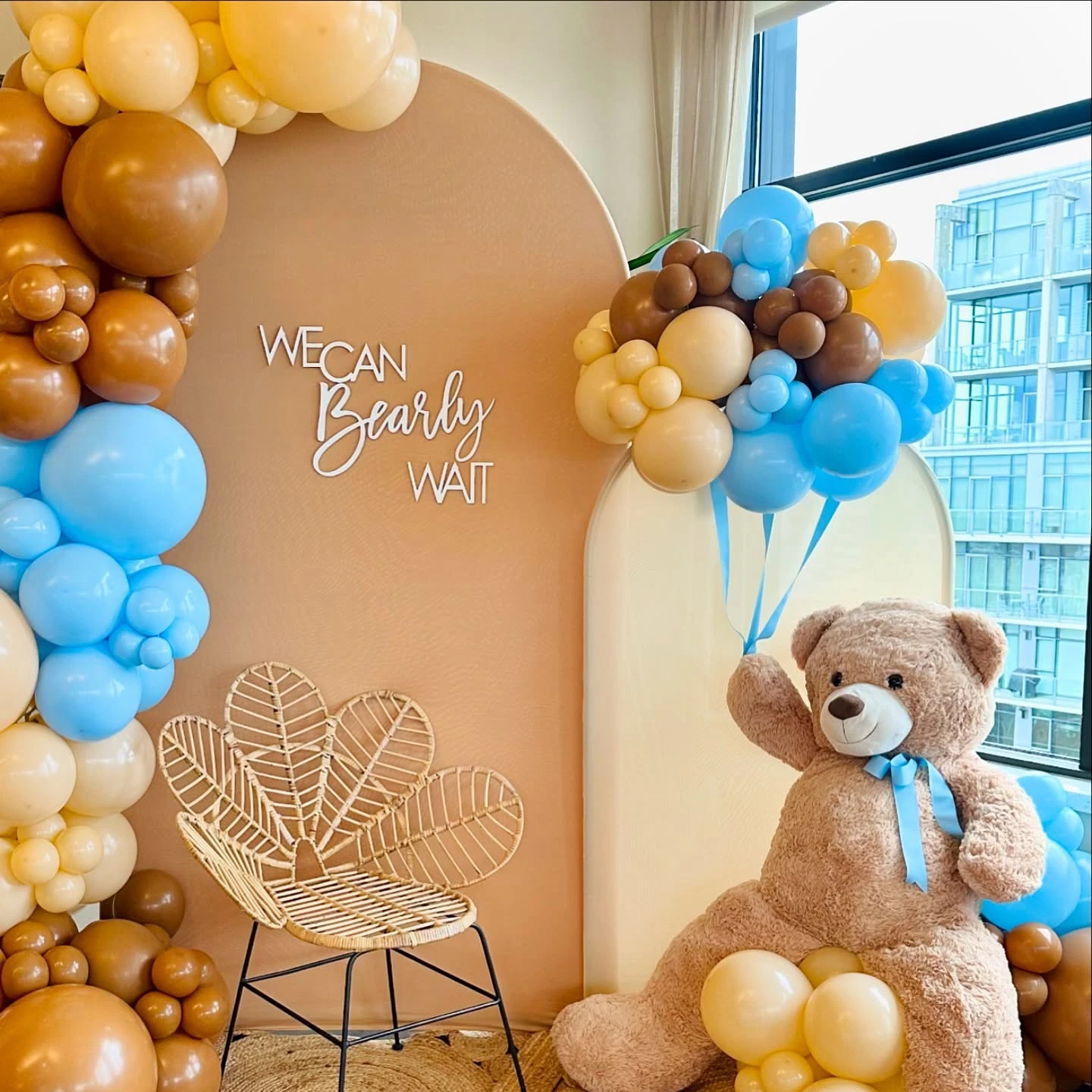 Full view of a teddy bear themed baby shower backdrop, highlighting the 'We Can Bearly Wait' sign on an arched panel.