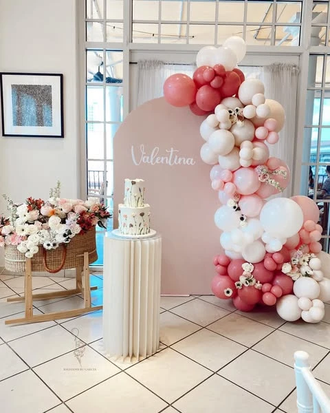A wildflower themed baby shower dessert station with a cake on a pedestal and a large floral basket.