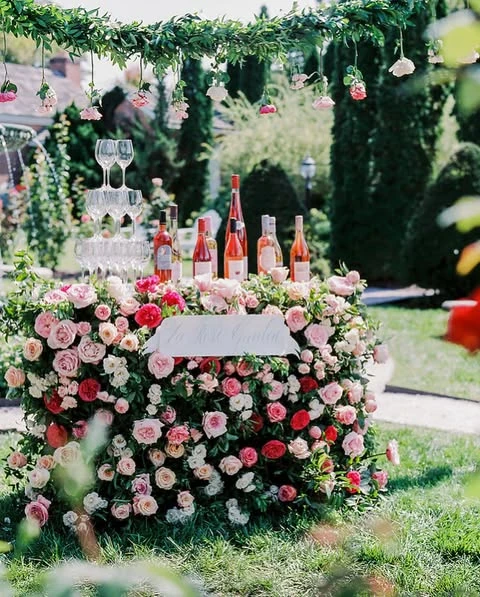 An outdoor rosé bar covered in fresh pink and red roses for a spring bridal shower.
