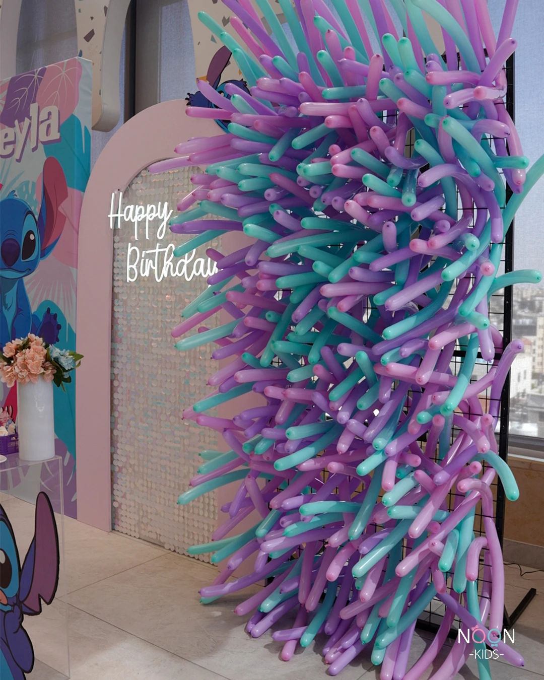 Unique balloon wall backdrop with teal, purple, and pink modeling balloons.