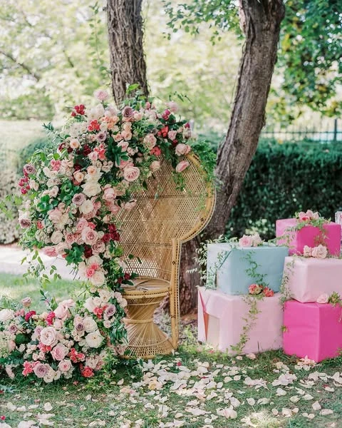A decorated rattan peacock chair with a large floral arrangement for a bride-to-be.