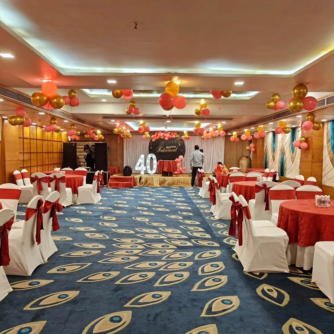 A wide view of a retirement party reception hall with a photo backdrop at the front.