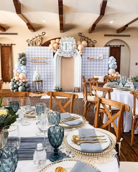 Elegant Peter Rabbit baby shower tablescape with blue glassware and gold cutlery.