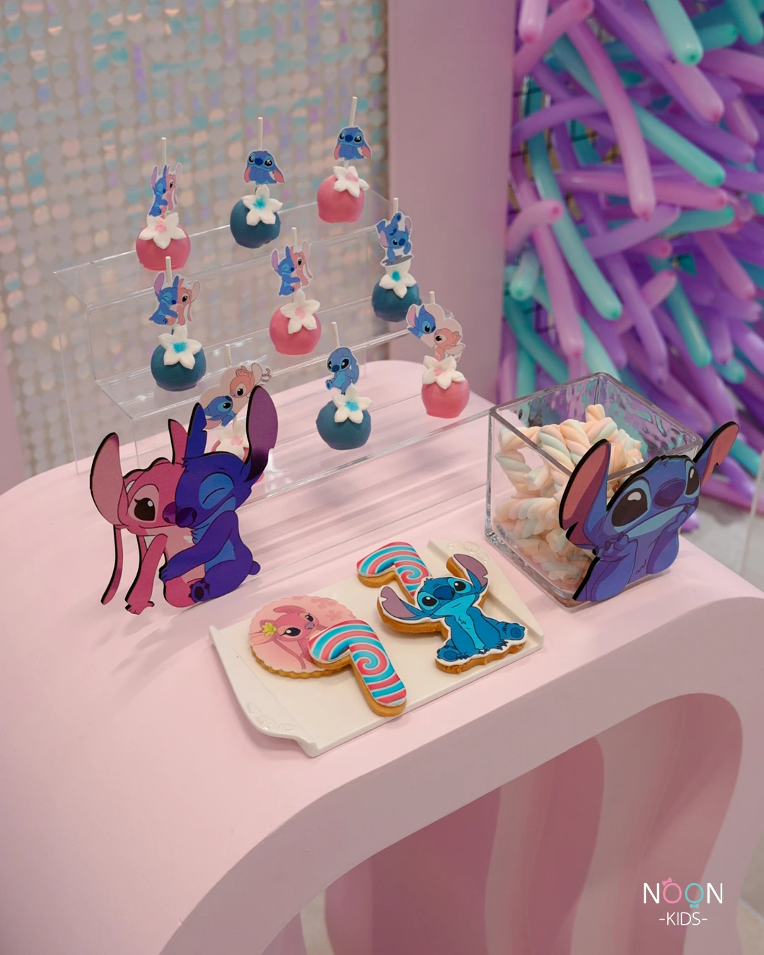 Stitch and Angel themed cake pops and cookies on a dessert display.