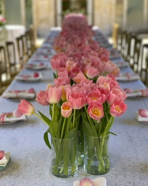 of a table runner made from multiple glass vases filled with pink tulips for a spring party.