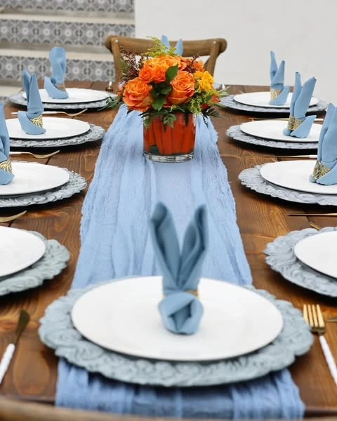 Peter Rabbit baby shower table setting with blue bunny ear napkins and a carrot centerpiece.