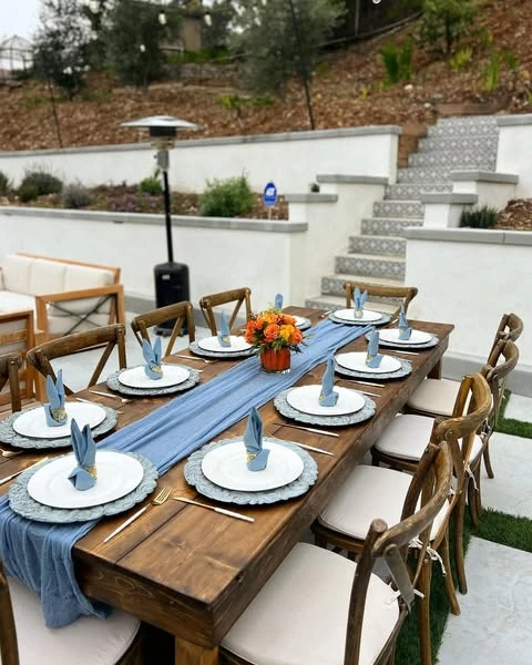 Long wooden dining table decorated for a Peter Rabbit baby shower with a blue runner.