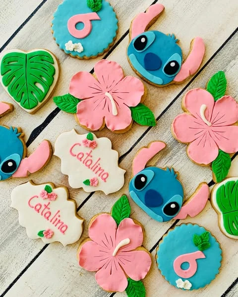 Assortment of custom Stitch-themed birthday cookies featuring Stitch, hibiscus flowers, and personalized plaques.