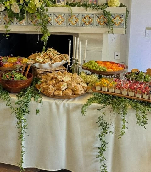 Baby shower food table showing tiered serving with sandwiches in a raised basket and individual appetizer cups.