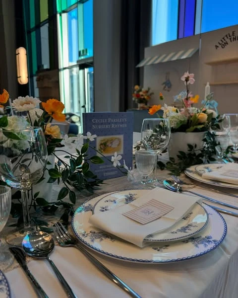 A Peter Rabbit themed baby shower tablescape with a storybook and blue floral plates.