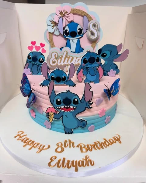 A two-tiered Stitch birthday cake with pink and blue ombre frosting and multiple character toppers.