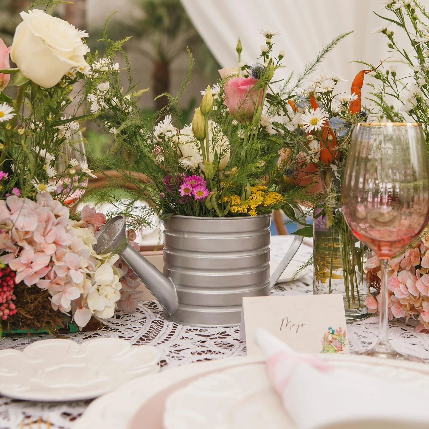 Table centerpiece featuring a small galvanized watering can filled with wildflowers next to a place setting.